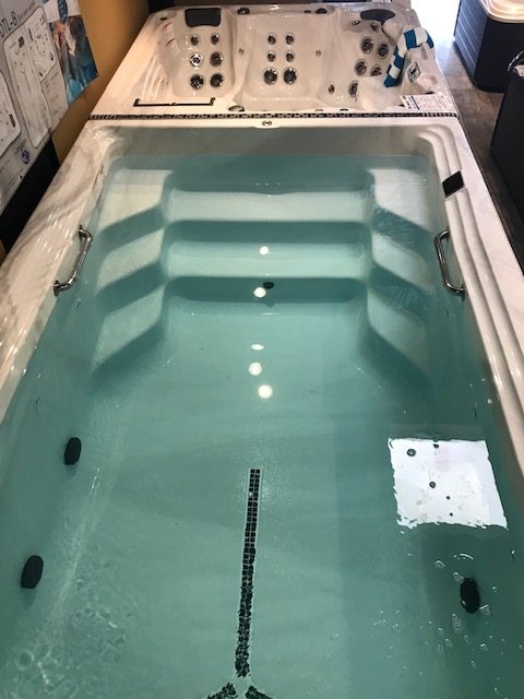 A water-filled swim spa with entry steps